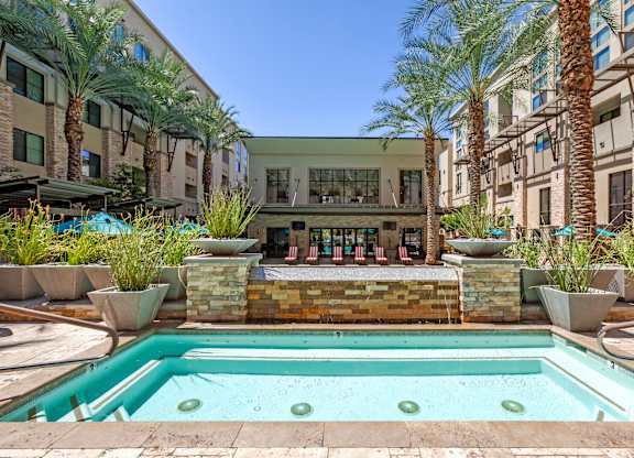 A pool surrounded by palm trees and a stone wall.