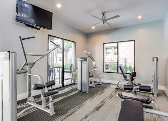 A well-equipped home gym with a television and a fan.