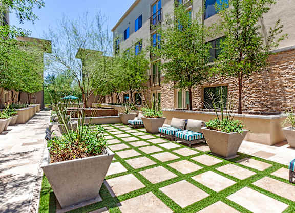 A courtyard with a green lawn and a white planter.