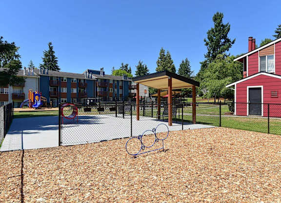 A playground with a basketball hoop and a red building in the background. at Brookstone, SeaTac, WA