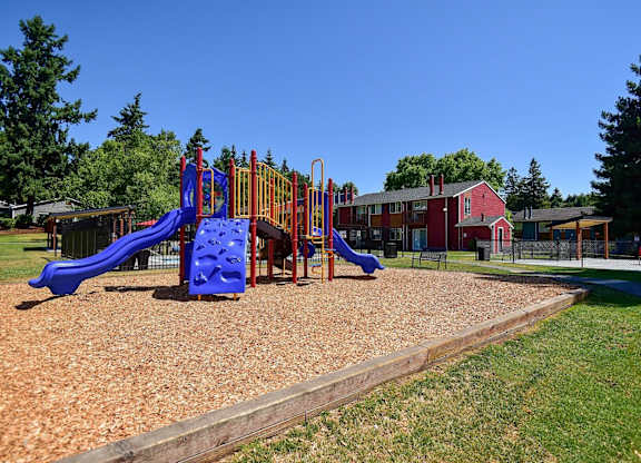 A playground with a blue slide and a red and yellow play structure. at Brookstone, SeaTac