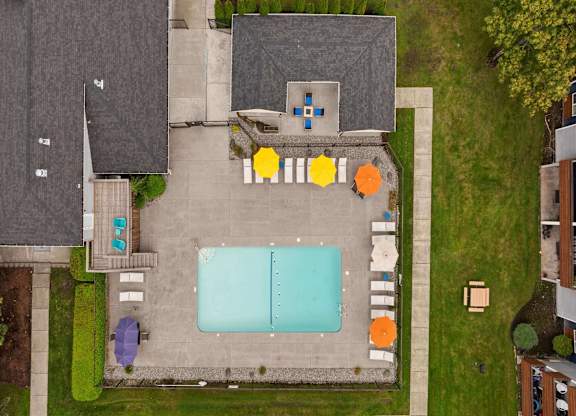 A pool surrounded by a concrete patio and a grassy area. at Northpoint Apartments, Washington