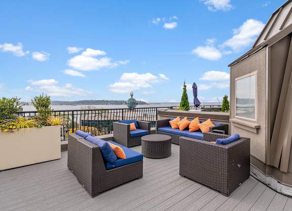 A patio with a couch, table, and chairs overlooking a body of water.