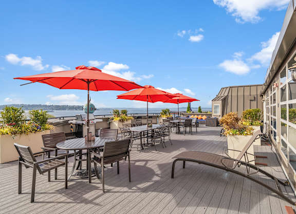 A patio with red umbrellas and wooden flooring.