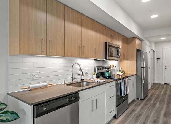 a kitchen with white cabinets and stainless steel appliances and a sink at Baldwyn, Seattle, WA 98125