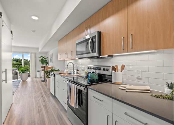 a modern kitchen with white cabinets and stainless steel appliances at Baldwyn, Seattle Washington