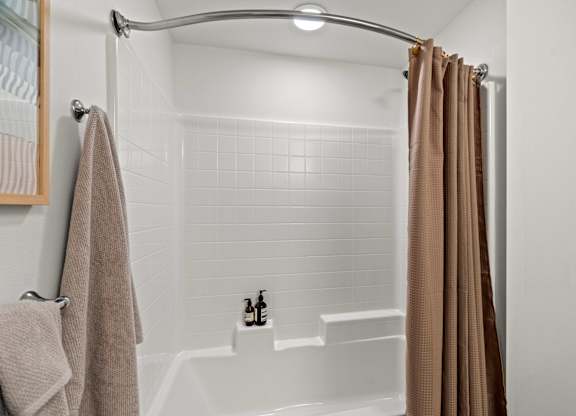A white shower with white tiles and light brown shower curtain at Baldwyn, Washington, 98125