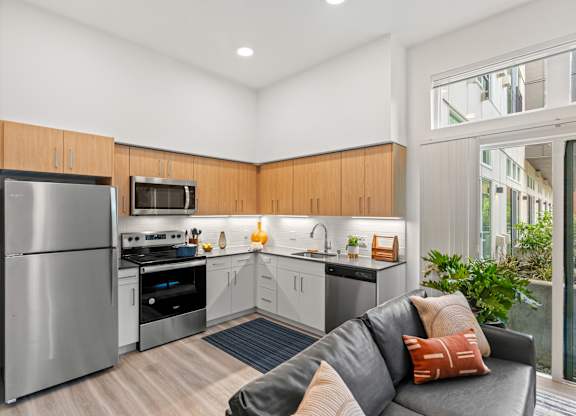 a living room with a couch and a kitchen with stainless steel appliances at Baldwyn, Seattle