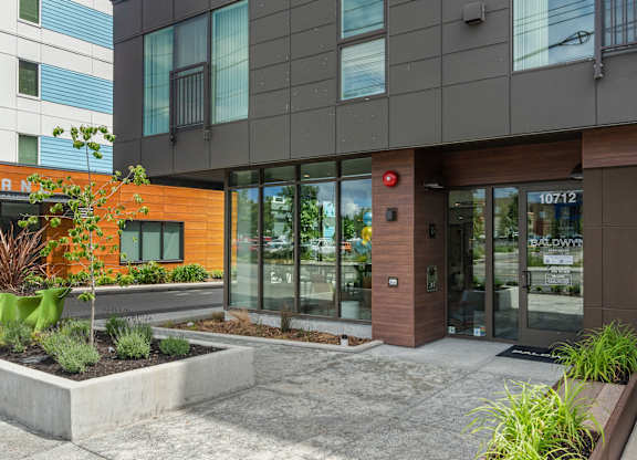 front entrance of a building with glass doors and a sidewalk at Baldwyn, Seattle, WA