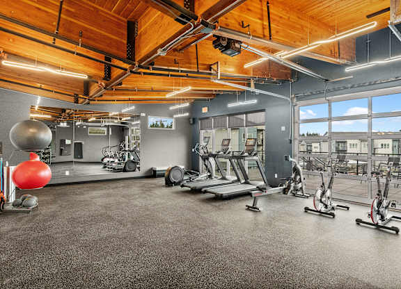 A gym with a variety of exercise equipment including treadmills, stationary bikes, and weights.
