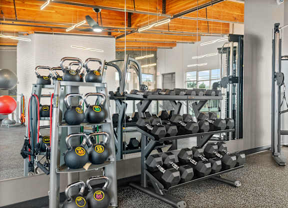 A gym with a variety of equipment including kettlebells and dumbbells.