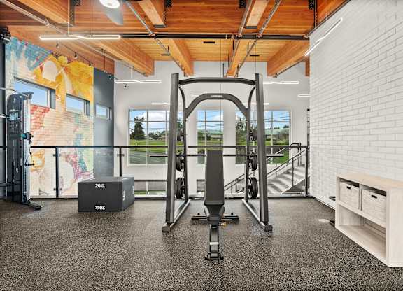 A gym with a squat rack, a weight bench and a wall with a mural.