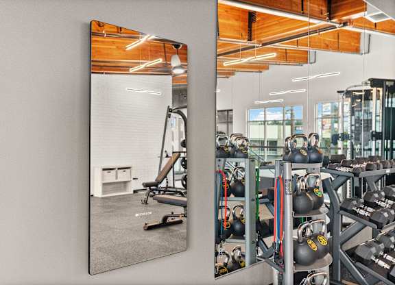 A gym with a mirror reflecting a workout area.