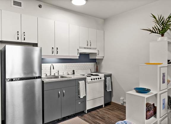 A modern kitchen with a refrigerator, sink, stove, and cabinets.