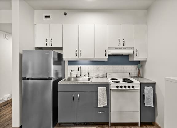 A modern kitchen with a stainless steel refrigerator and white cabinets.