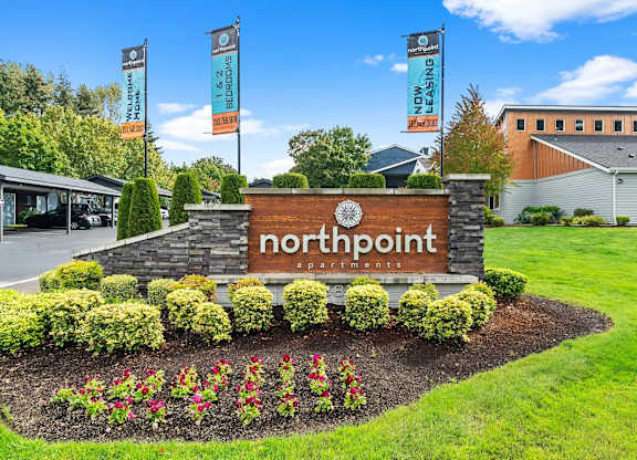 A sign for Northpoint Apartments is surrounded by flowers and greenery. at Northpoint Apartments, Tacoma, Washington