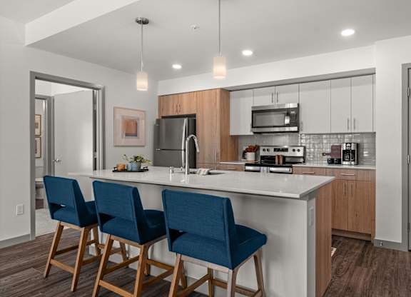 a kitchen with a large island with three blue chairs at Gage On Sixth, Washington