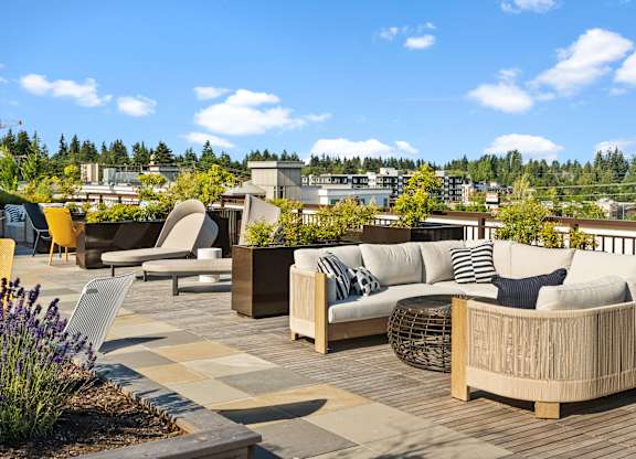 a roof top patio with couches and chairs and plants at Baldwyn, Seattle, WA 98125