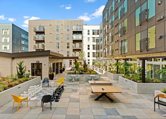 an outdoor patio with tables and chairs and buildings in the background at Baldwyn, Seattle, WA