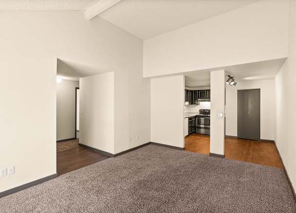 A large, empty room with a carpeted floor and white walls.