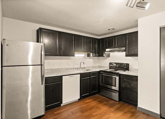 A modern kitchen with a stainless steel refrigerator and black cabinets.