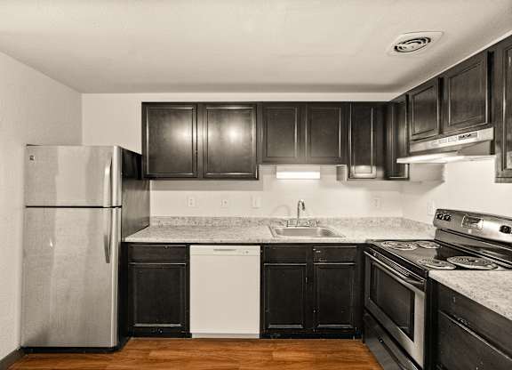 A kitchen with black cabinets and a stainless steel refrigerator.