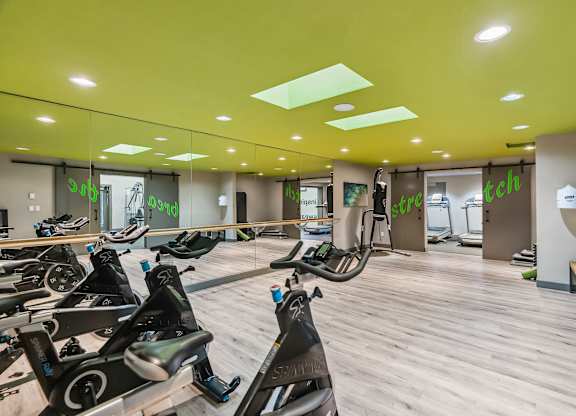 A gym with a row of stationary bikes.
