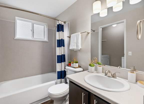 A bathroom with a white bathtub, toilet, and sink.