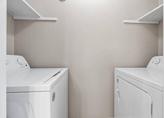 Two white front loading washing machines in a laundry room.