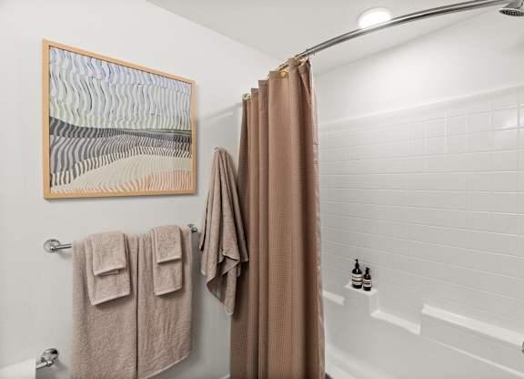 a bathroom with a shower and towels and a shower curtain