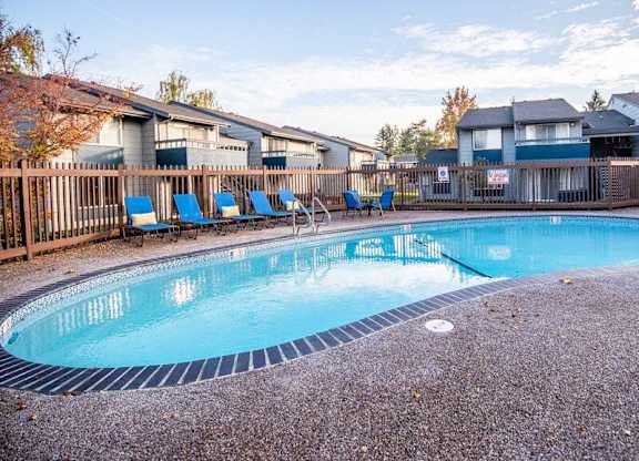 A large outdoor swimming pool surrounded by a fence and chairs. at The Lakes at Fife, Fife, WA
