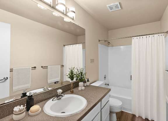 A bathroom with a sink, mirror, and shower.