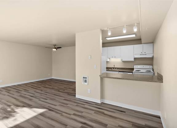 A room with a ceiling fan and a kitchenette area.