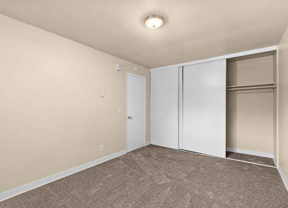 A room with a carpeted floor and a white closet.