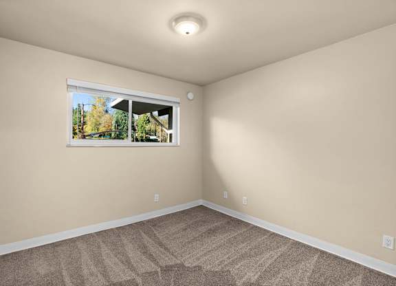 A room with a carpeted floor and a window showing an outdoor view.