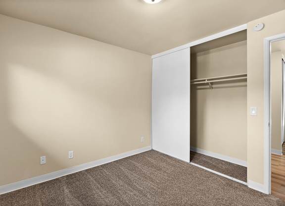 A room with a white door and a carpeted floor.
