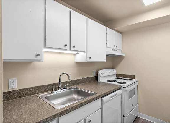 A kitchen with white cabinets and a stove top oven.
