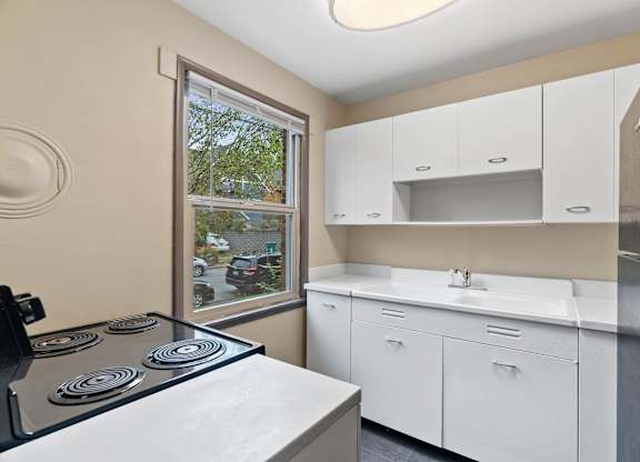 A kitchen with a stove top oven and white cabinets.