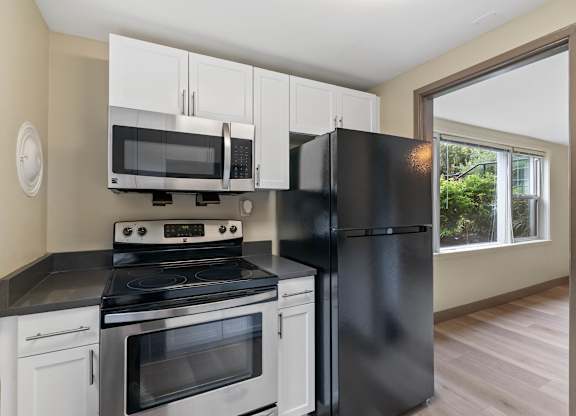 A black refrigerator stands next to a stove in a kitchen.
