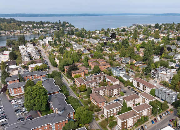 A bird's eye view of a residential area with houses and a body of water in the distance.