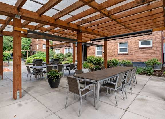 A wooden pergola with a table and chairs underneath.