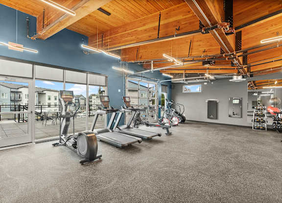 A gym with a variety of equipment including treadmills, weights, and exercise machines.