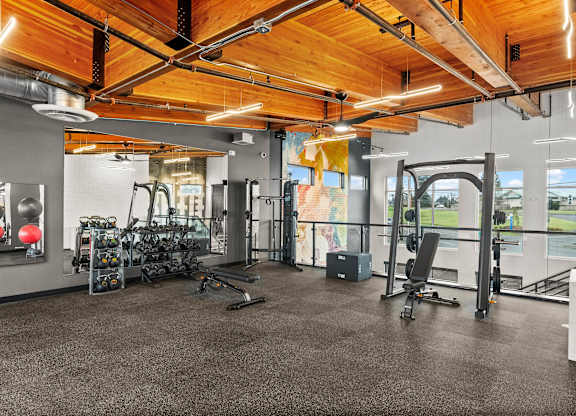 A gym with a variety of equipment including treadmills, weights, and exercise machines.