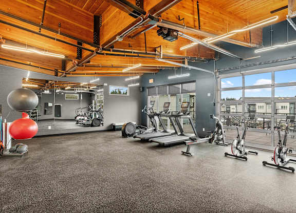 A gym with a variety of exercise equipment including treadmills, stationary bikes, and weights.