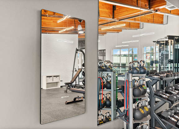 A gym with a mirror reflecting a workout area.
