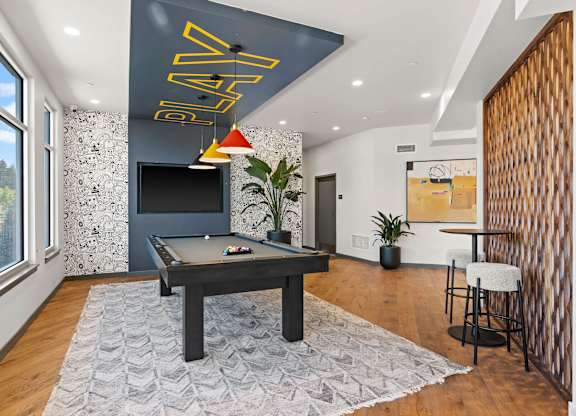 A room with a pool table and a TV mounted on the wall.