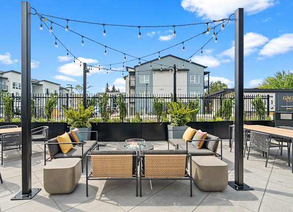 A patio with a table and chairs under a string of lights.
