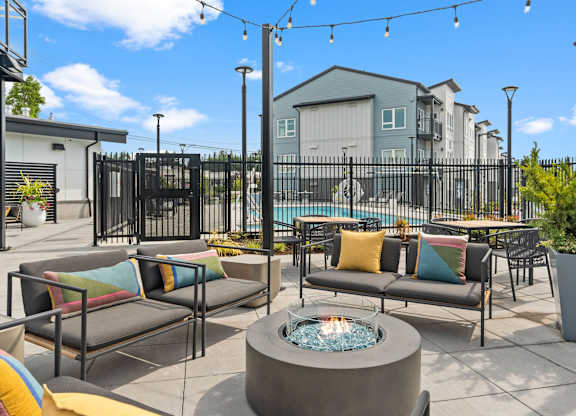 A patio with a fire pit and couches.