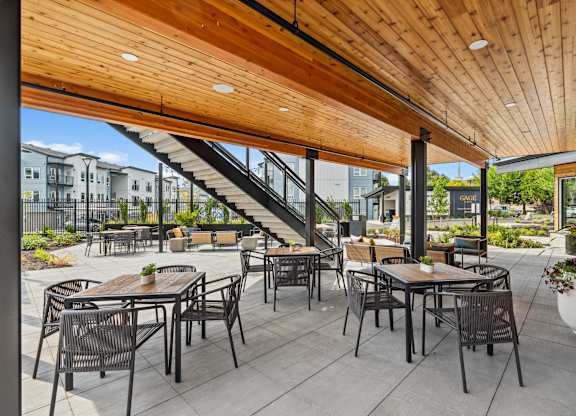 A patio with tables and chairs and a staircase.