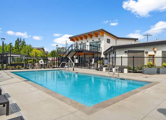 A large swimming pool in front of a building with a black fence around it.